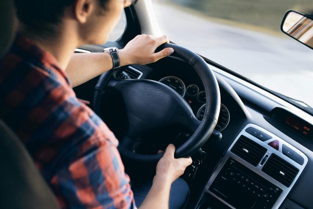 Vyro, vairuojančio modernų automobilį, vaizdas iš arti, matyti prietaisų skydelis ir vairo mechanizmo detalės.